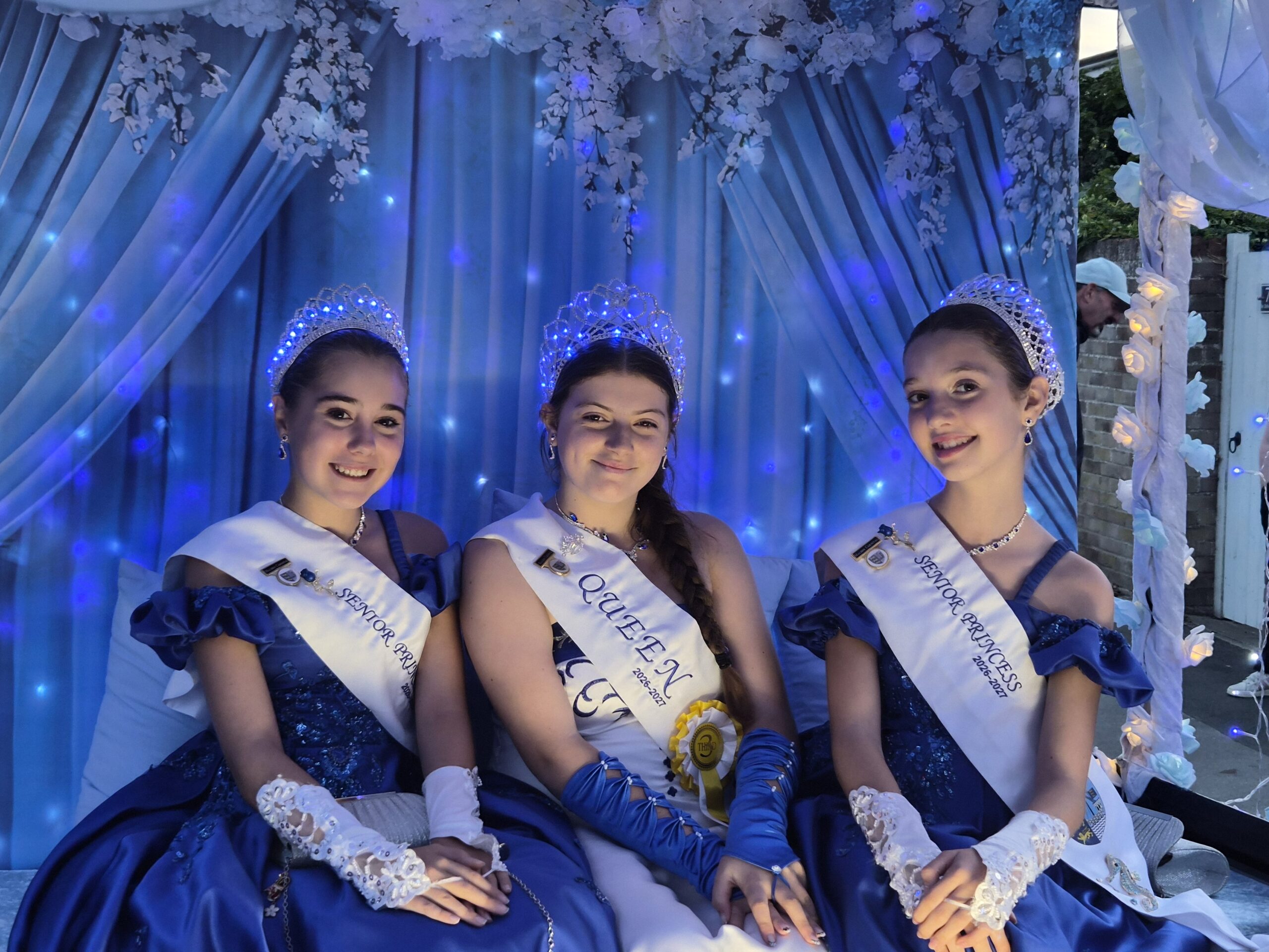 Maldon Carnival Court wearing blue and white gowns on their illuminated float